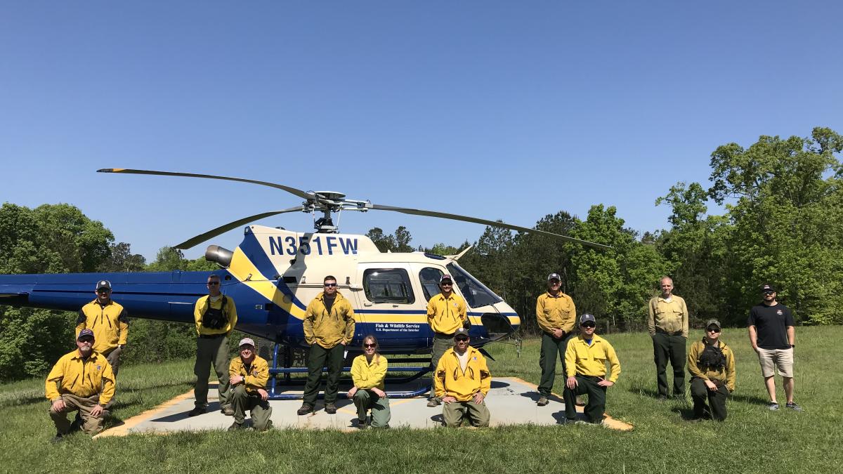 Group of people posing in front of a helicopter