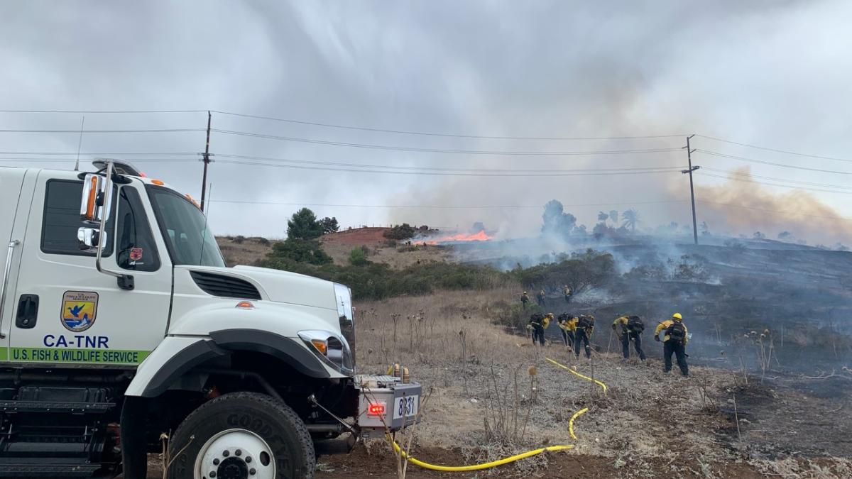 Large work truck with firefighters in the background