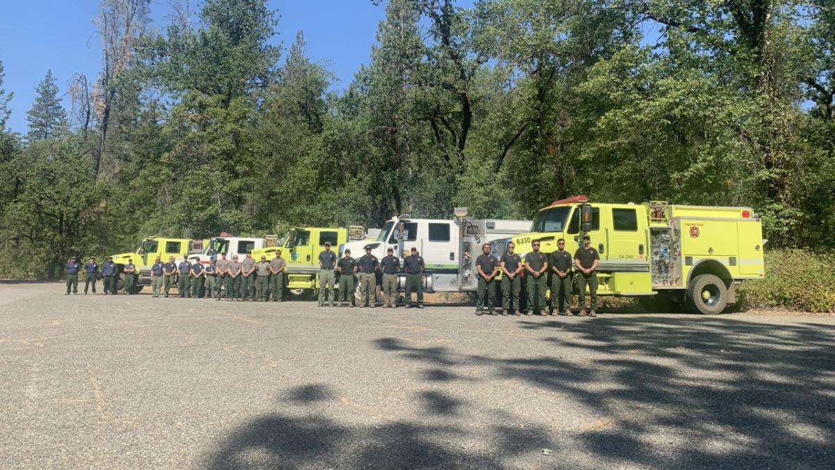 Group photo of individuals standing in front of work vehicles