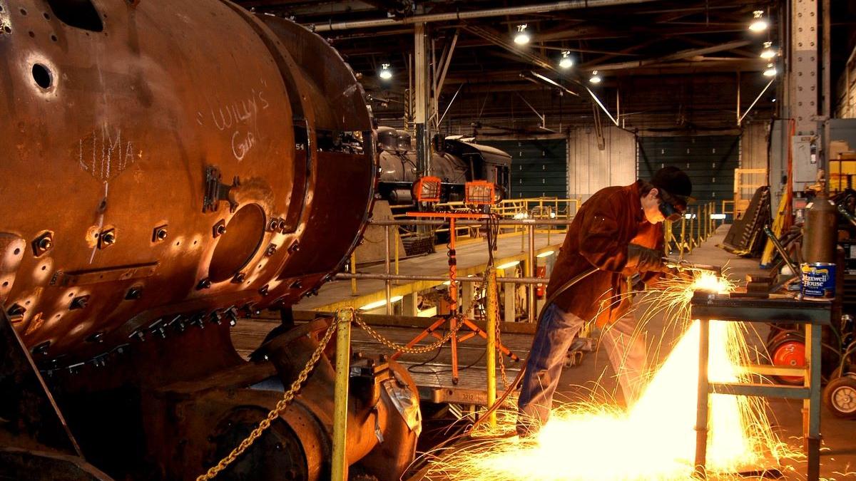 A mechanic create sparks while grinding metal in the Locomotive Shops at Steamtown NHS