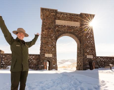A park ranger next to the Roosevelt Arch near the park's North Entrance in Gardiner, Montana, on a winter day. NPS / Jacob W. Frank