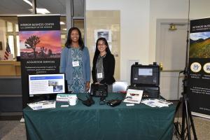Two female contracting officers from the DOI Interior Business Center at a display table