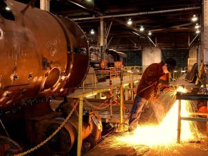 A mechanic create sparks while grinding metal in the Locomotive Shops at Steamtown NHS